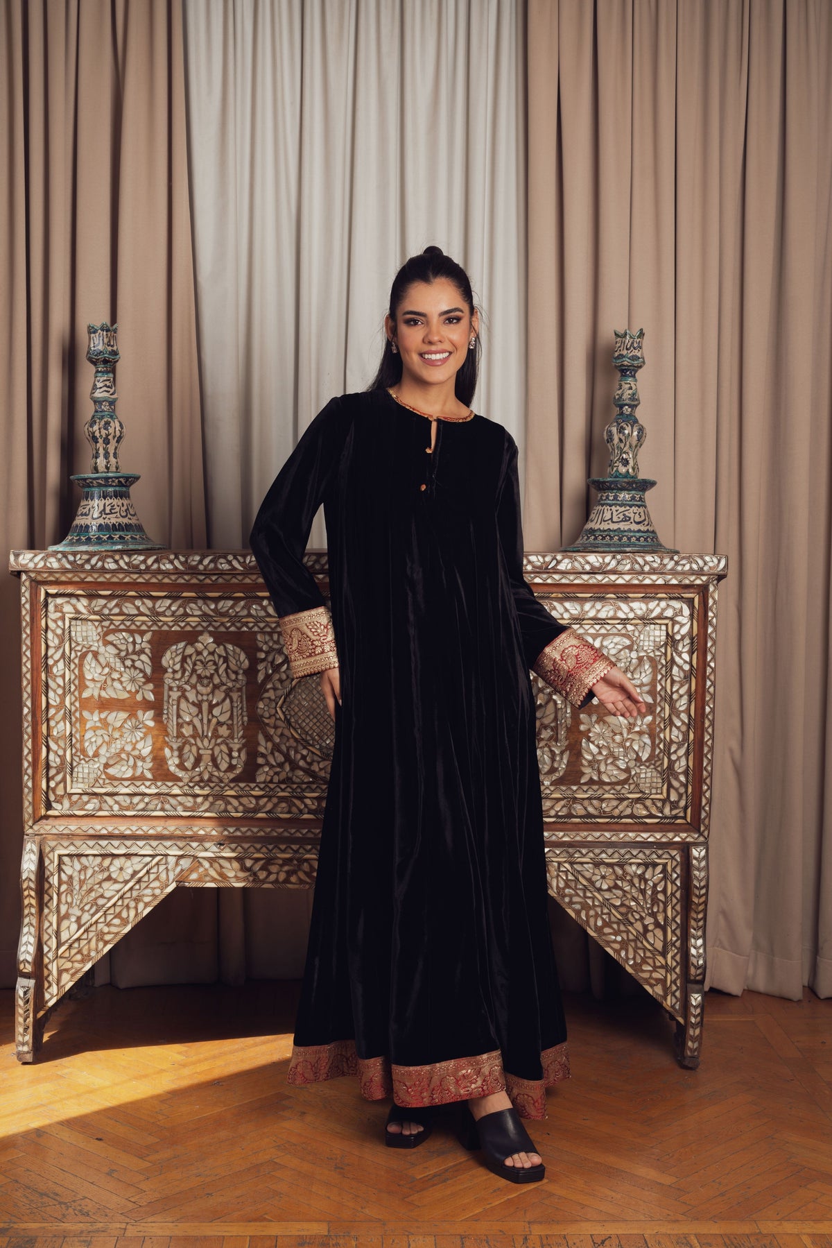 A timeless black velvet kaftan featuring intricate gold and red
